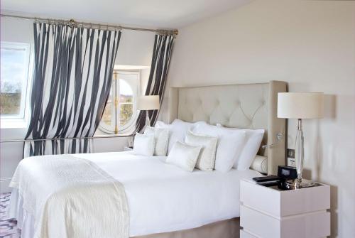 凡尔赛Waldorf Astoria Versailles - Trianon Palace的白色的卧室设有白色的床和窗户。