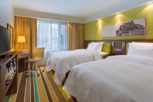华沙华沙市中心希尔顿汉普顿酒店的酒店客房设有两张床、一张桌子和一台电视。