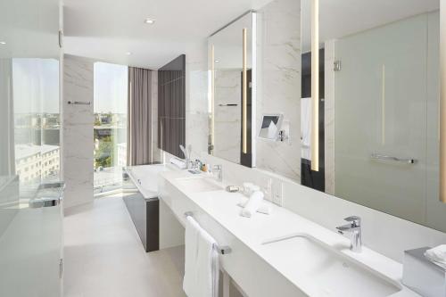 塔林希尔顿塔林公园酒店的一间带三个水槽和大镜子的浴室