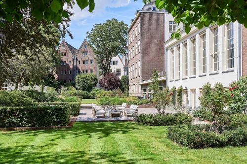 阿姆斯特丹阿姆斯特丹华尔道夫酒店的一座带桌椅的花园,以及一座建筑