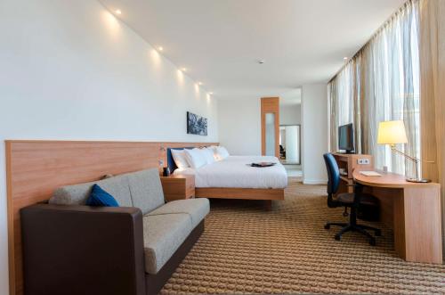 阿姆斯特丹Hampton By Hilton Amsterdam Arena Boulevard的酒店客房配有一张床、一张沙发和一张书桌。