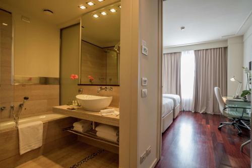 佛罗伦萨希尔顿佛罗伦萨大都市酒店的一间带水槽和浴缸的浴室以及一张床