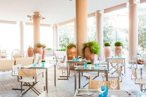 佛罗伦萨佛罗伦萨诺弗里希尔顿花园酒店的餐厅设有桌椅和大窗户。