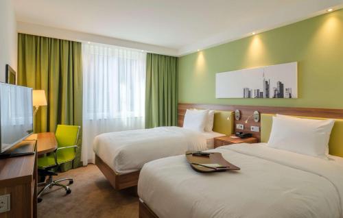 美因河畔法兰克福Hampton by Hilton Frankfurt City Centre的酒店客房设有两张床、一张桌子和一台电视。