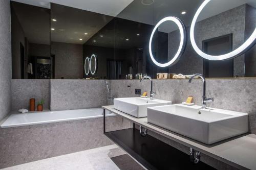 曼海姆Hilton Garden Inn Mannheim的浴室配有2个盥洗盆、浴缸和镜子