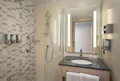 基尔Hampton By Hilton Kiel的浴室配有盥洗盆和带镜子的淋浴