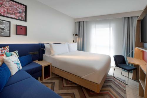 凯撒斯劳滕Hampton By Hilton Kaiserslautern的酒店客房,配有床和蓝色的沙发