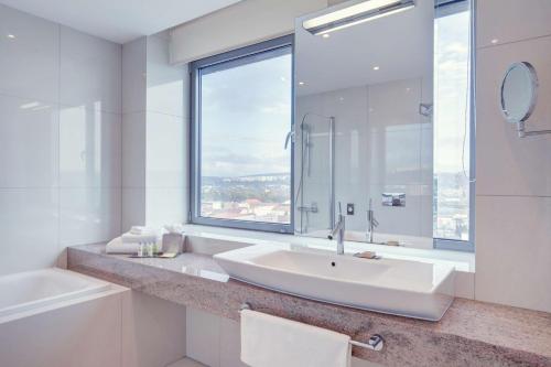 科希策科希策希尔顿逸林酒店的白色的浴室设有水槽和窗户。