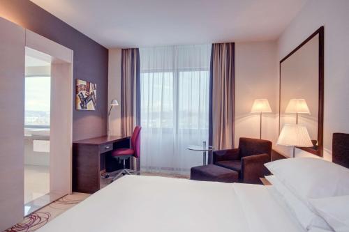 科希策科希策希尔顿逸林酒店的配有一张床和一把椅子的酒店客房