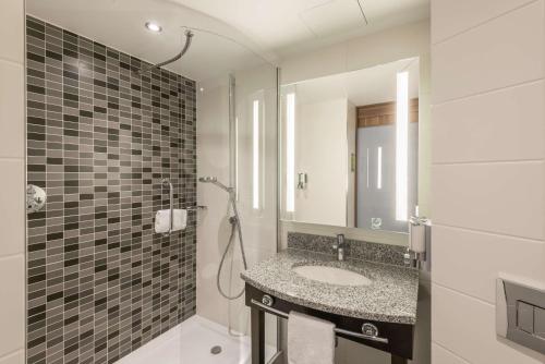慕尼黑Hampton By Hilton Munich City West的浴室配有盥洗盆和带镜子的淋浴