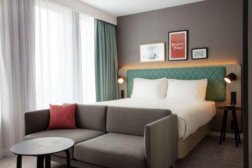 朗吉斯Hilton Garden Inn Paris Orly Airport的酒店客房,配有床和沙发