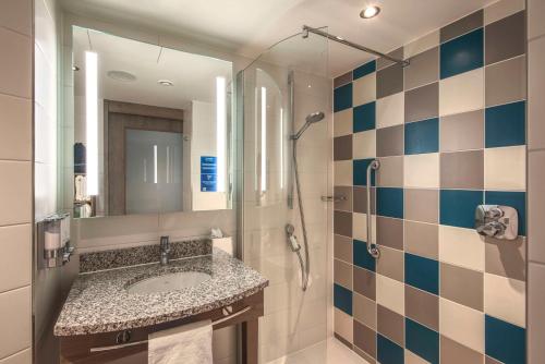 斯图加特Hampton by Hilton Stuttgart City Centre的一间带水槽、淋浴和镜子的浴室