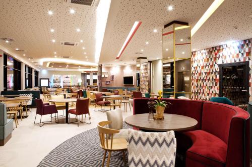 维也纳Hampton By Hilton Vienna Messe的一间带桌椅和红色沙发的餐厅