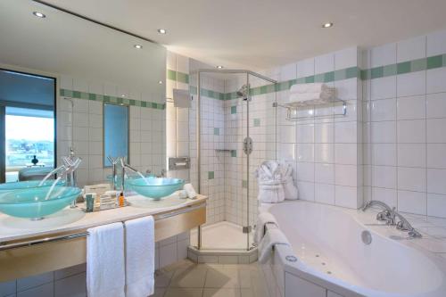 欧普菲康希尔顿苏黎世机场酒店的浴室配有两个盥洗盆和浴缸。