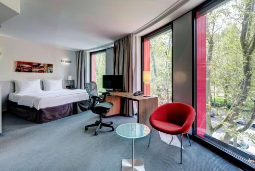 斯图加特斯图加特希尔顿酒店耐卡公园店的酒店客房配有一张床、一张桌子和一把红色椅子