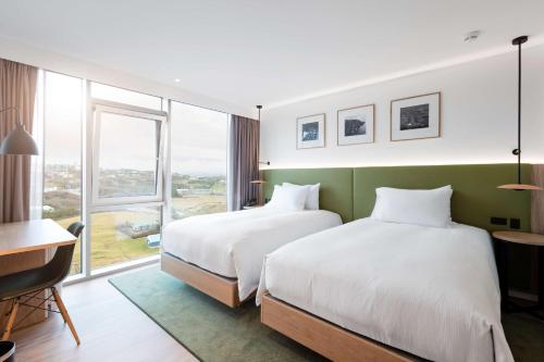 托尔斯港Hilton Garden Inn Faroe Islands的酒店客房设有两张床和窗户。