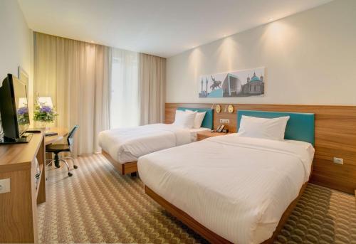 乌法乌法汉普顿希尔顿酒店的酒店客房设有两张床、一张桌子和一台电视。