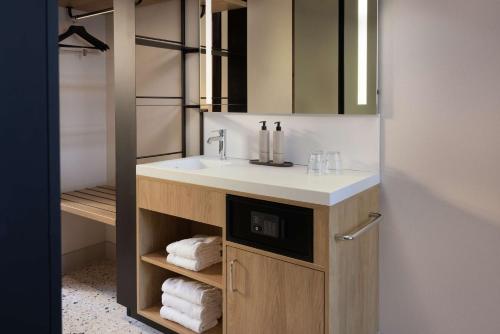 鹿特丹Motto By Hilton Rotterdam Blaak的浴室配有盥洗盆、镜子和毛巾