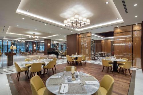 斯科普里DoubleTree By Hilton Skopje的一间带桌椅和钢琴的餐厅