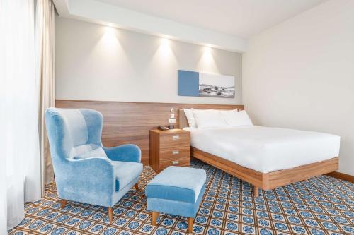 奥斯威辛Hampton by Hilton Oswiecim的酒店客房,配有一张床和一张蓝色椅子
