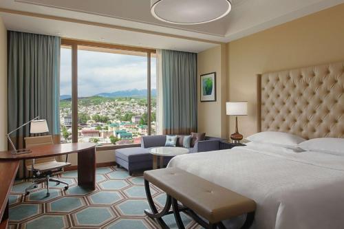 杜尚别Hilton Dushanbe的酒店客房设有一张床和一张书桌,享有美景。