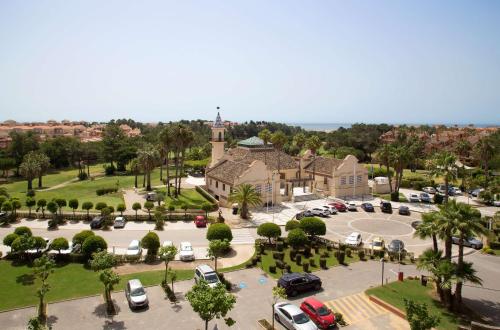伊斯兰蒂拉DoubleTree by Hilton Islantilla Beach Golf Resort的教堂空中景色,设有停车场