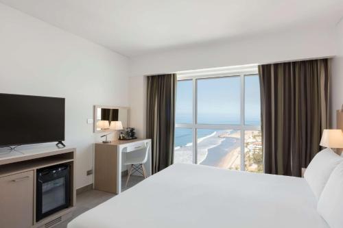 马萨特兰DoubleTree by Hilton Mazatlan, SIN的一间酒店客房,设有一张大床和一个大窗户