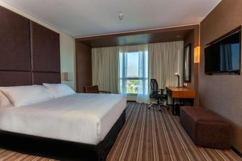 内乌肯Hilton Garden Inn Neuquen的酒店客房配有一张床、一张书桌和一台电视。