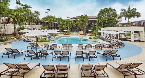 西班牙港特立尼达希尔顿会议酒店 的度假酒店的游泳池配有椅子和遮阳伞