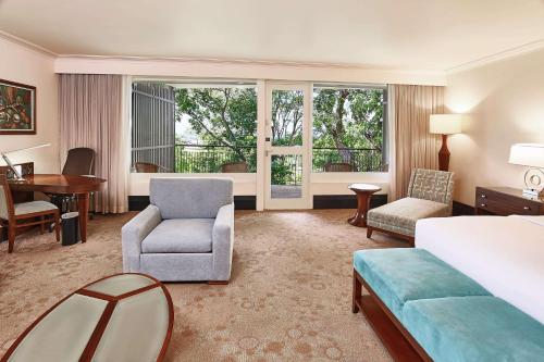 西班牙港特立尼达希尔顿会议酒店 的酒店客房,配有一张床、一张桌子和椅子