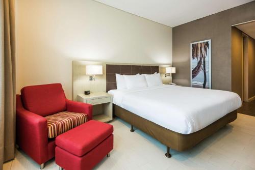 巴兰基亚巴兰基亚希尔顿花园酒店的一间卧室配有一张床和一张红色椅子