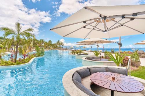帕皮提Hilton Hotel Tahiti的度假村的游泳池配有遮阳伞