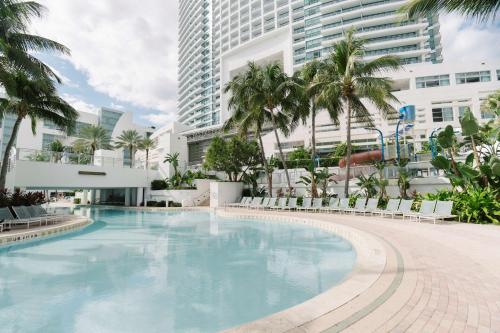 好莱坞好莱坞外交官海滩度假村 - 希尔顿Curio Collection酒店的一座棕榈树和建筑的大型游泳池