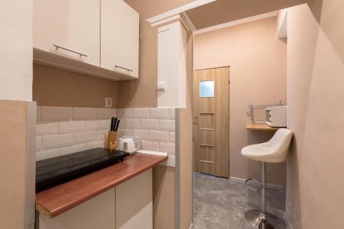 克拉科夫70s Guest room的厨房配有白色橱柜和木制台面