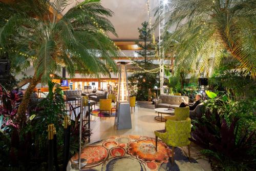 堪培拉北博恩凉亭酒店的大堂种植了棕榈树,配有桌椅