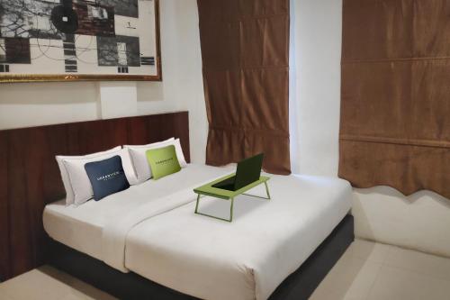棉兰Urbanview Os Residence Medan by RedDoorz的一间卧室配有一张带绿色笔记本电脑的床。