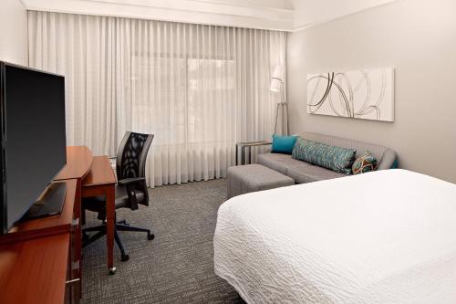 休斯顿Courtyard by Marriott Houston Rice University的配有床、书桌和电视的酒店客房