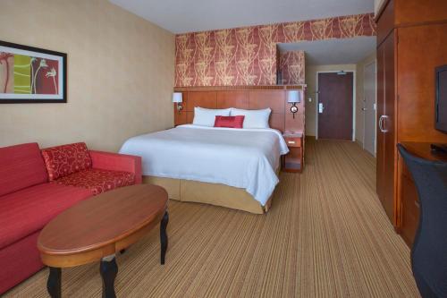 波士顿南波士顿万怡酒店的酒店客房,配有一张床和一张红色的沙发