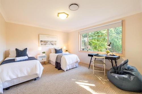 芬加尔湾White Sands, 14 Whitesands Road - Pet Friendly & Air Con的一间卧室设有两张床、一张桌子和一个窗口。