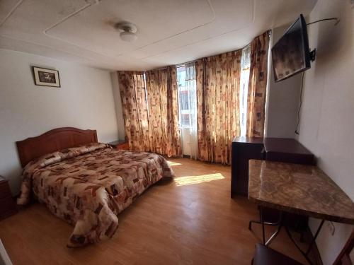 普诺HOSTAL SUMITA HOUSE_INN的一间卧室配有一张床、一张书桌和一台电视
