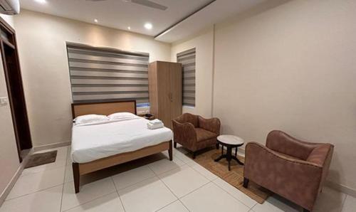 海得拉巴FabHotel Prime AM Suites Near Yashoda Hospital的一间卧室配有一张床和一把椅子