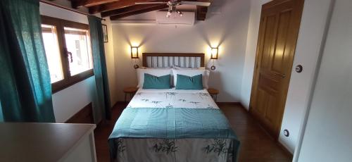 新埃斯特班德拉斯Buhardilla Ca'tio Celso的一间卧室配有一张带蓝色枕头的床和一扇窗户。