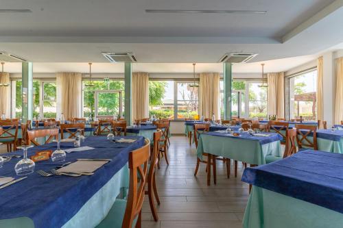 丽都迪萨维奥Hotel Concord的餐厅设有蓝色的桌椅和窗户。