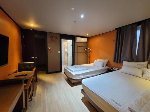 釜山Foxy Hotel的酒店客房配有两张床和一张书桌
