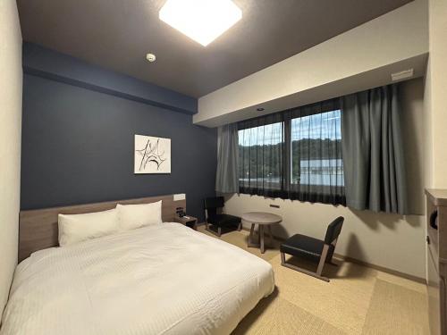 秩父市Hotel Route Inn Grand Chichibu的一间卧室配有一张床、一张桌子和一个窗户。