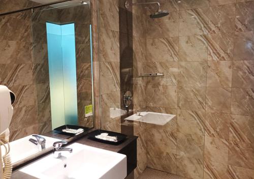 名古屋King's Hotel Nagoya Batam的浴室配有盥洗盆和带镜子的淋浴