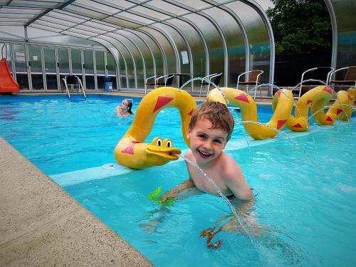 兰讷斯Randers City Camp的有一个小孩在游泳池里,有黄色天鹅