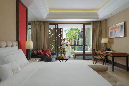 塞米亚克特兰斯巴厘岛度假村的一间卧室配有一张床,一对夫妇站在阳台上
