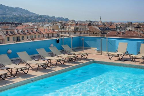 尼斯NH尼斯酒店的一个带椅子的游泳池,享有城市美景