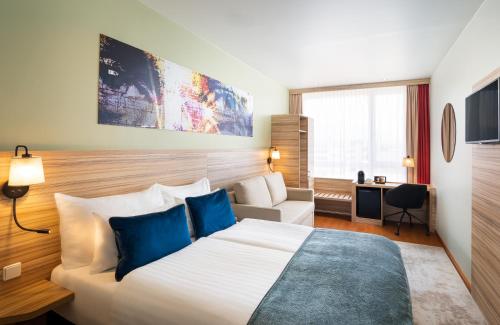 萨尔茨堡Leonardo Hotel Salzburg Airport的酒店客房设有一张大床和一张沙发。